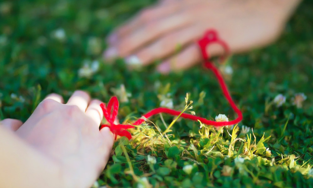 小指を赤い糸で結ばれたカップル